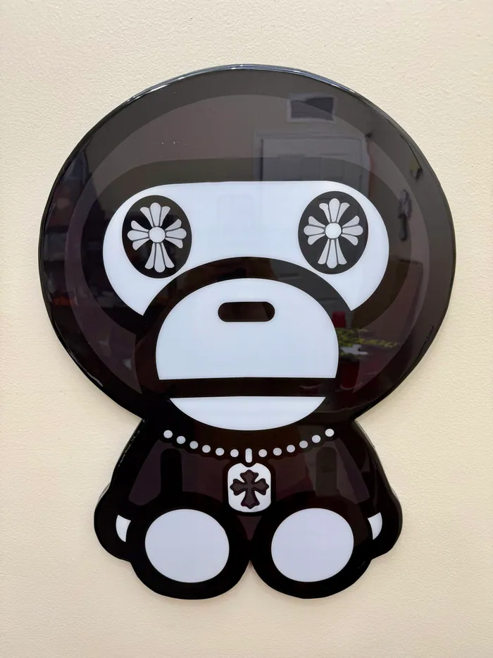 A black-and-white cartoon ape with cross-shaped eyes, in glossy epoxy on a wall
